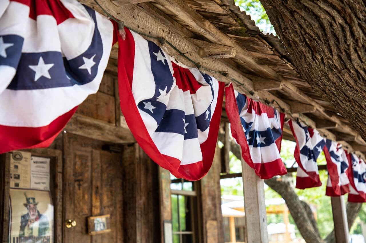bunting flags on the porch eaves of a rustic building beside a tree