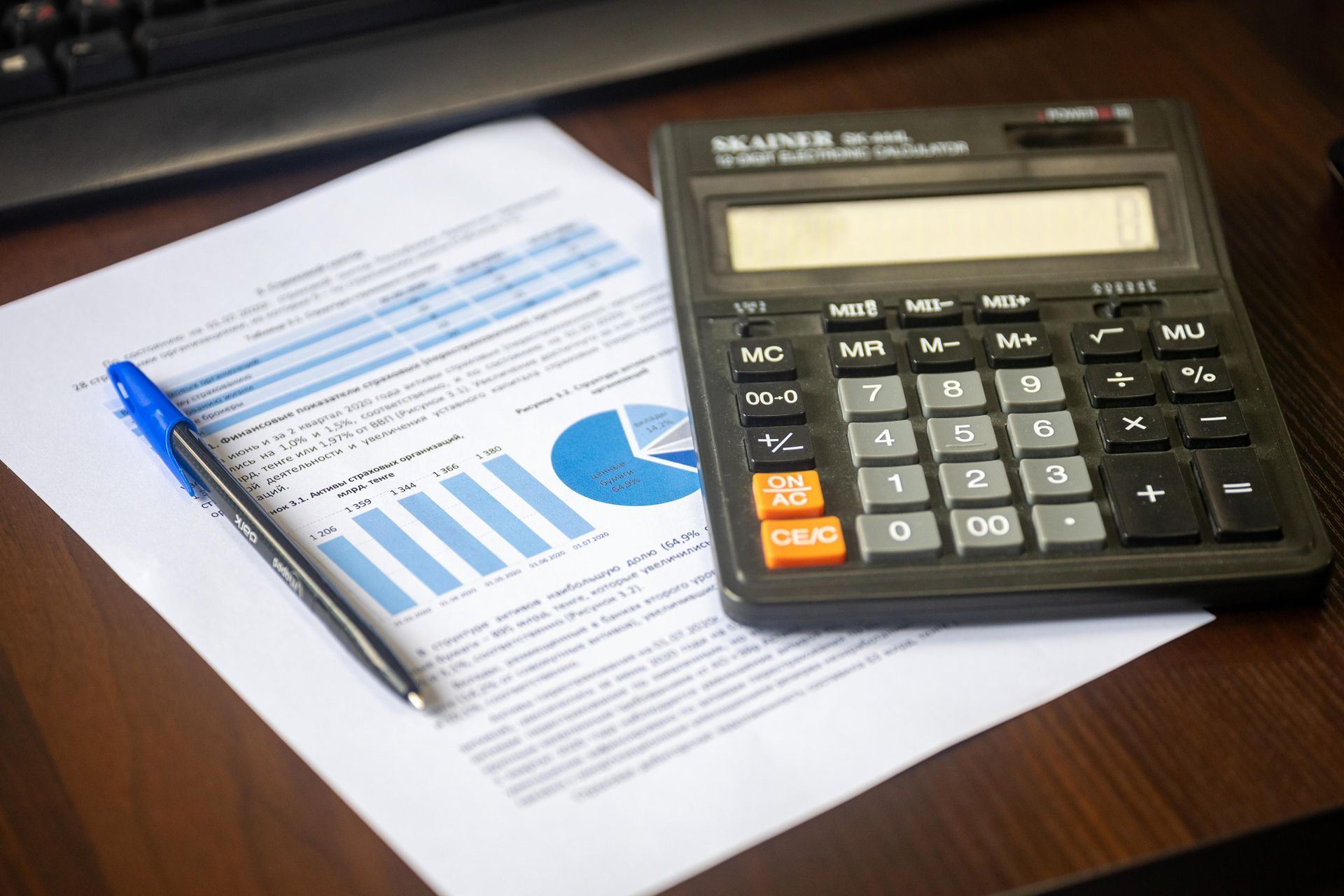 Calculator and pen resting on a financial report on a desk.