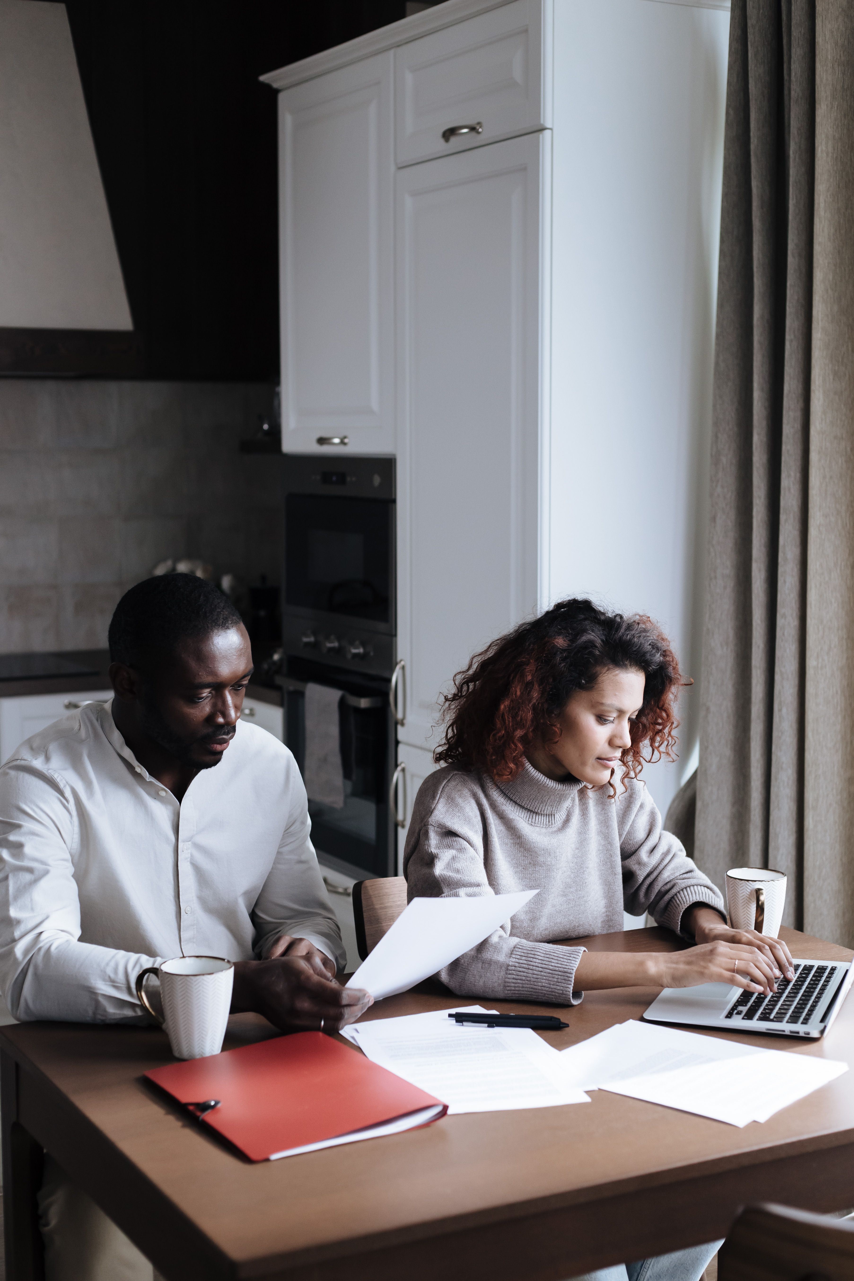 Couple reviewing documents with a laptop at home.