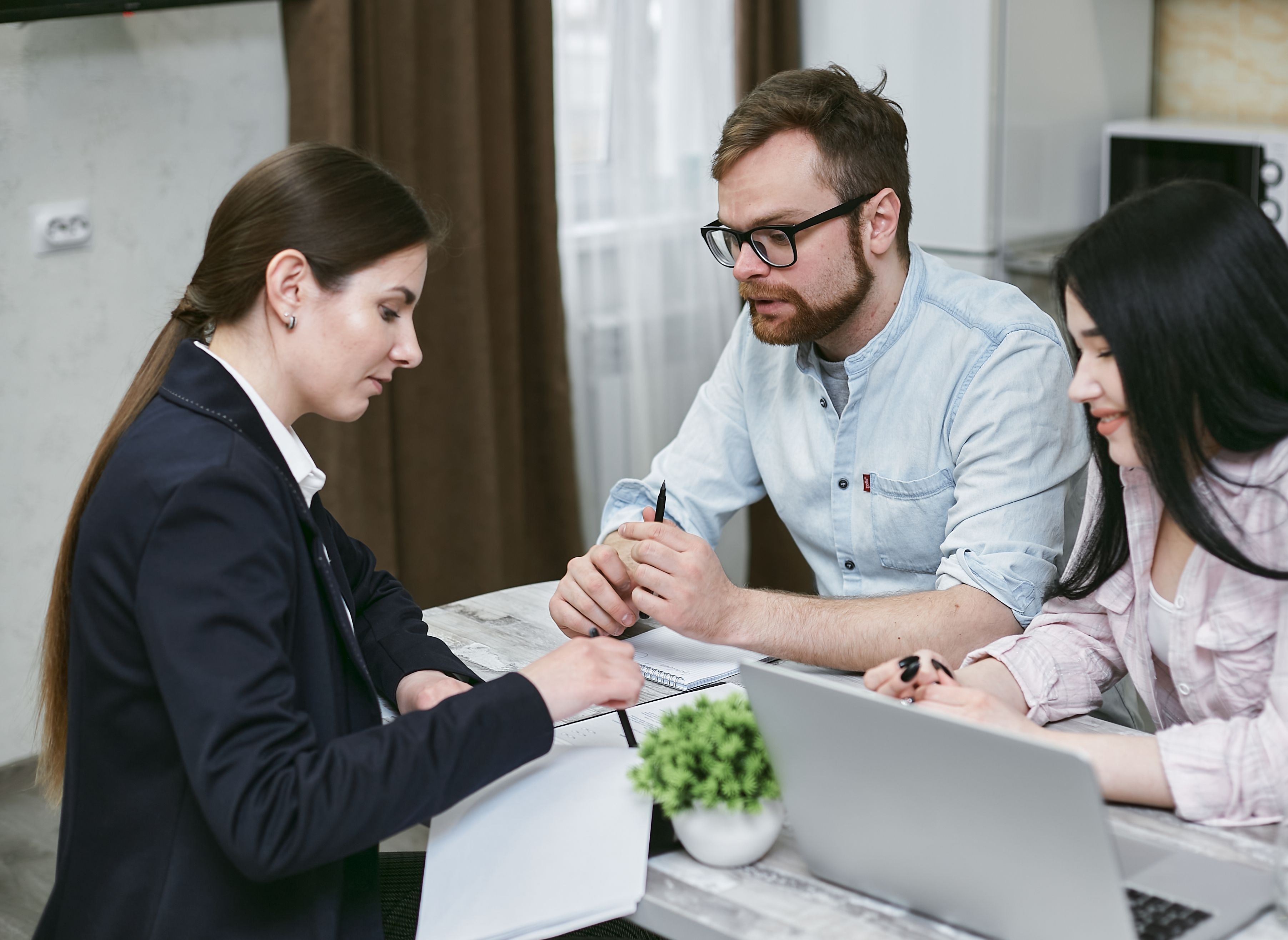 Couple reviewing documents with an advisor during a conversation.