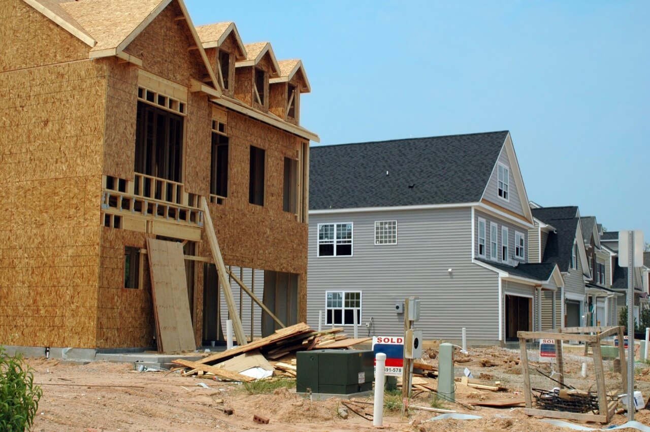 New-construction subdivision with an unfinished osb-sheathed house framed in the foreground