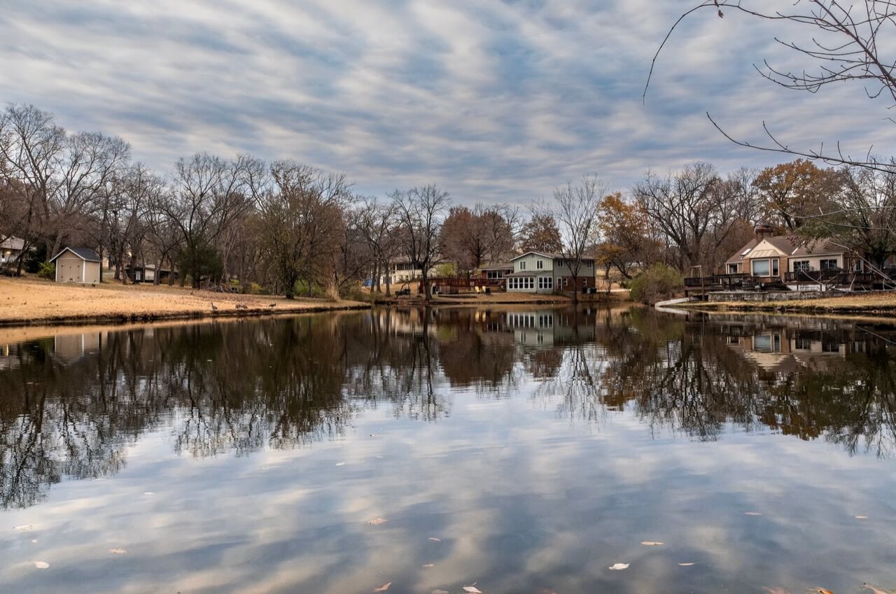 Calm lake in late autumn with suburban lakeside houses, decks and a small shed along the far shore
